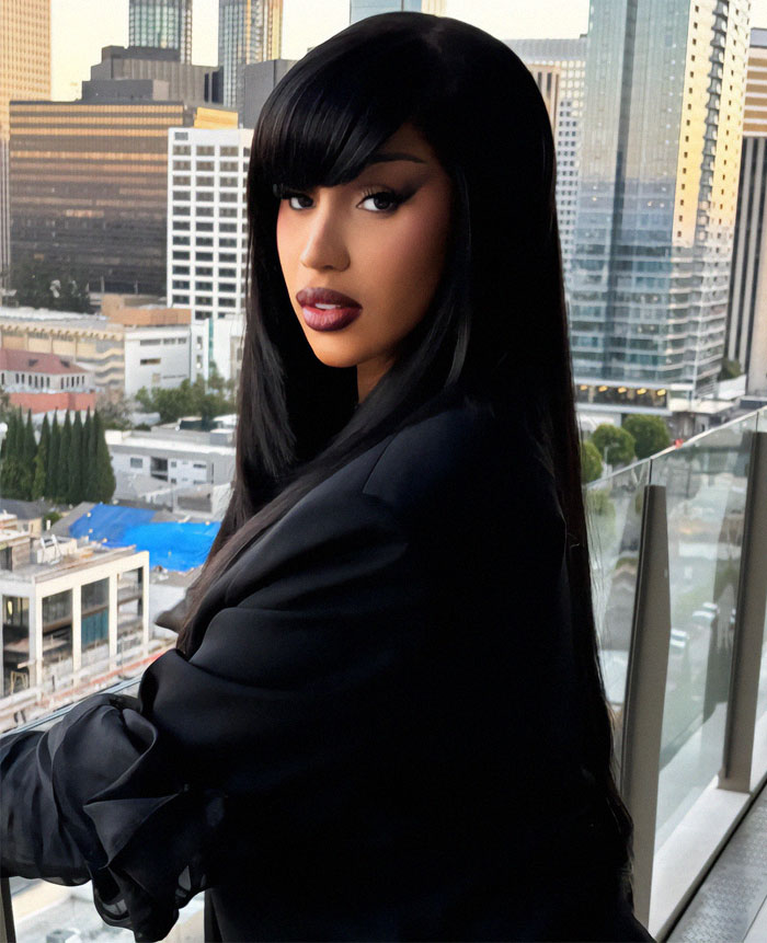 A person with long black hair, gazing over a cityscape from a balcony, related to a Superbowl party.