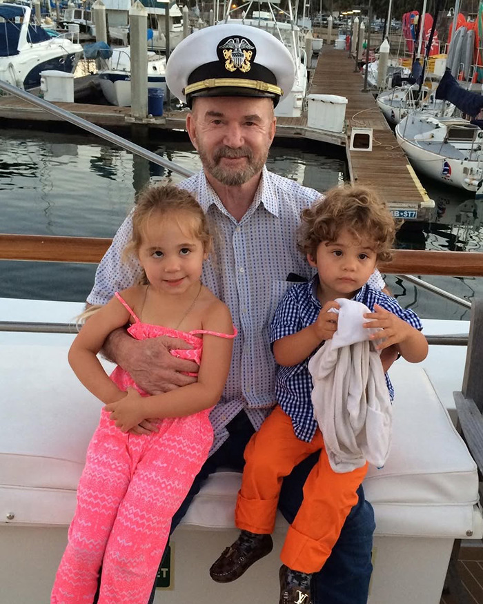 A veteran in a captain's hat with two children on a boat.