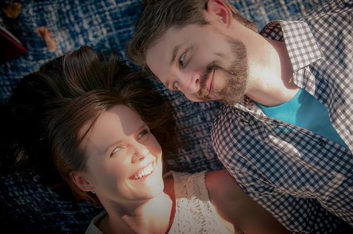 A couple lying on a blanket outside, smiling at each other, enjoying a sunny day, symbolizing a child-free lifestyle.