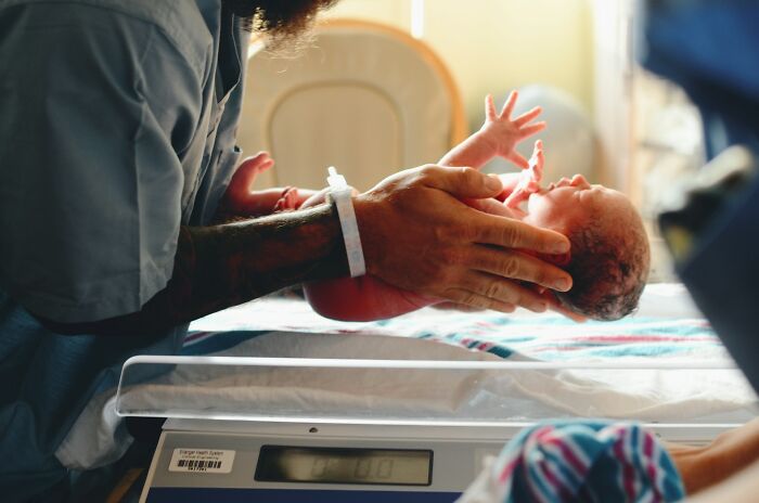 Newborn baby being weighed by a nurse.