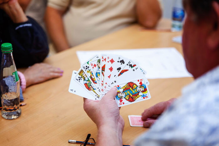 Person holding playing cards at a table, highlighting travel must-haves for entertainment.