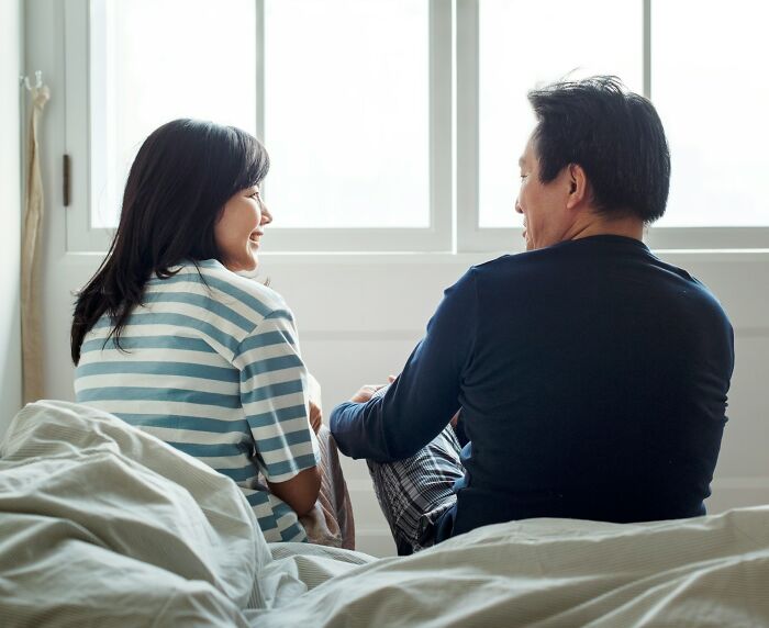 A couple sharing a conversation on a bed, with natural light streaming through a window; world perspective concept.