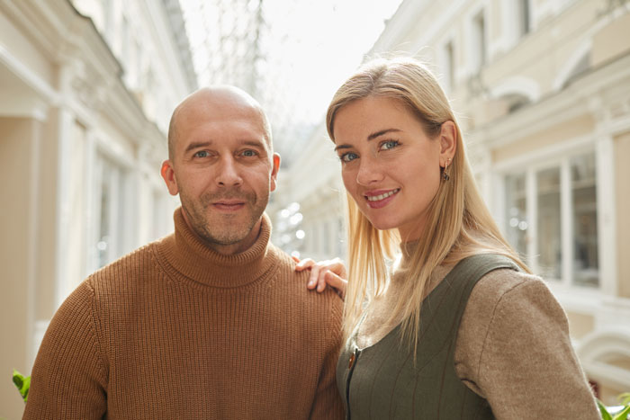 Man and woman posing together indoors, focusing on smiling and casual attire, relevant to theme of dad and girlfriend dynamics.