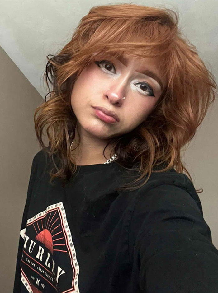 Single woman with auburn hair wearing a black shirt, showcasing a makeup style with glitter for protection on dates.