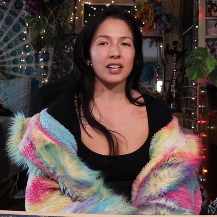 Person in colorful jacket, seated indoors with decor, reflecting BookTube crisis theme in a casual setting.