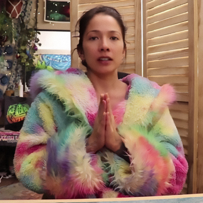 Person wearing a colorful fur coat with hands together, amid BookTube crisis discussion.