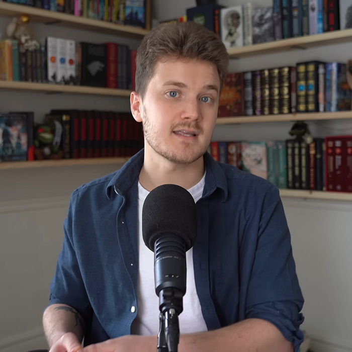 Person discussing BookTube crisis in a library setting with a microphone.