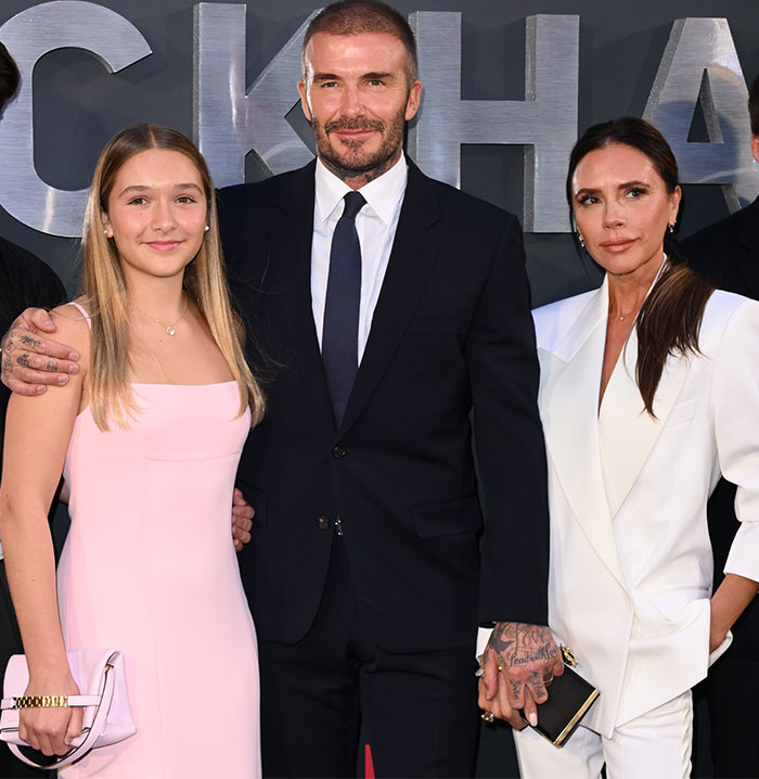 David Beckham with daughter Harper in a pink dress and family at an event.