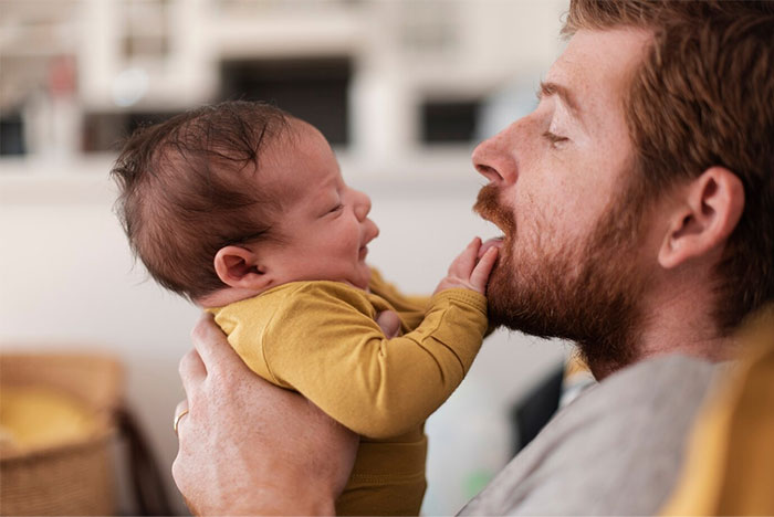 Father holding infant son, highlighting family dynamics and parental responsibility.