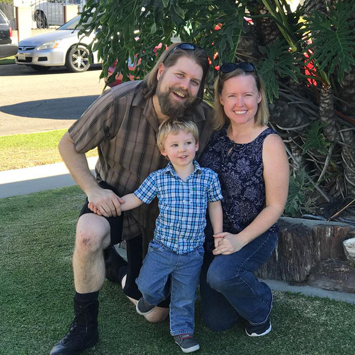 A family of three smiling outdoors near a tree, related to a Disney worker's story with an AI tool.