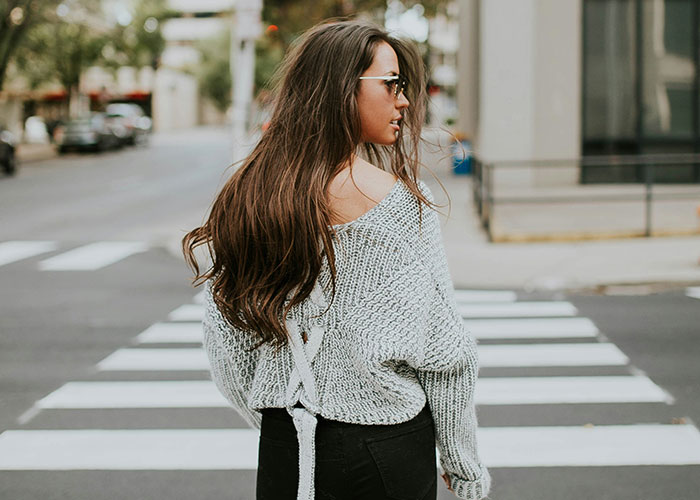 Woman crossing the street, highlighting fashion and lifestyle, related to job probation and punctuality issues.