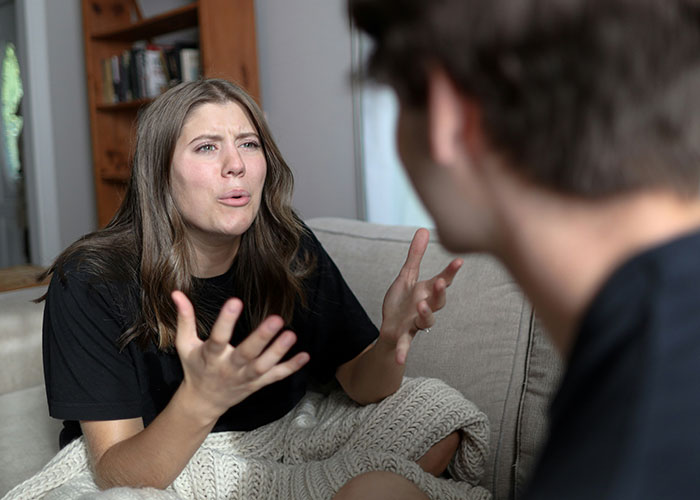 Woman frustrated during conversation on a sofa, discussing a job probation issue.