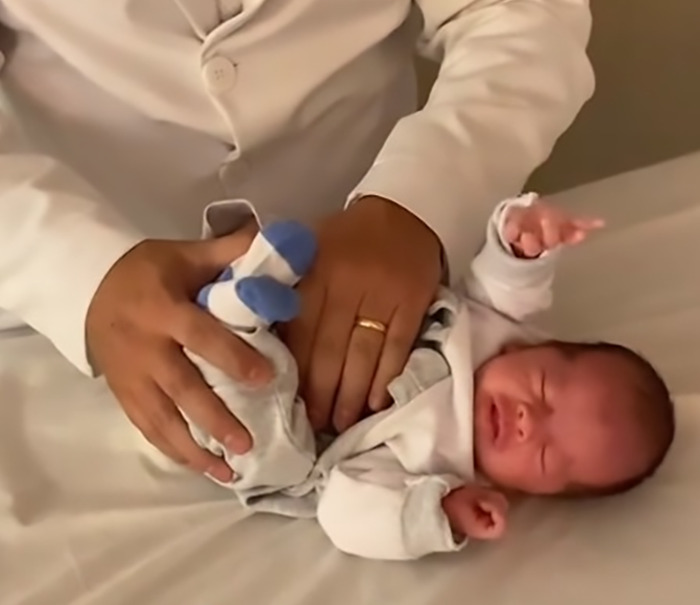 Doctor demonstrating baby farting tips on a newborn, evoking humorous reactions.