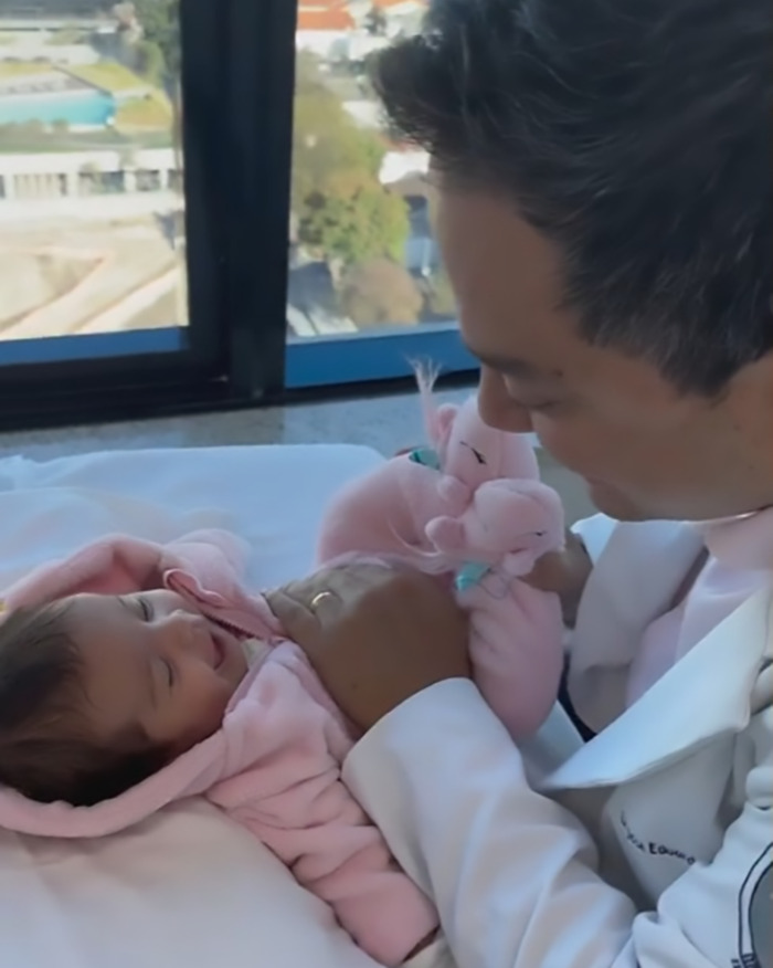 Doctor in a white coat gently interacting with a smiling baby in a pink outfit, highlighting baby farting tips.