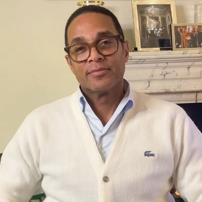 A person in glasses and a white cardigan near a mantel with framed photos, related to Bianca Censori controversy.