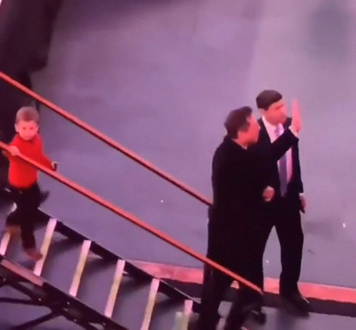 Elon Musk on stairs with his child X in a red shirt