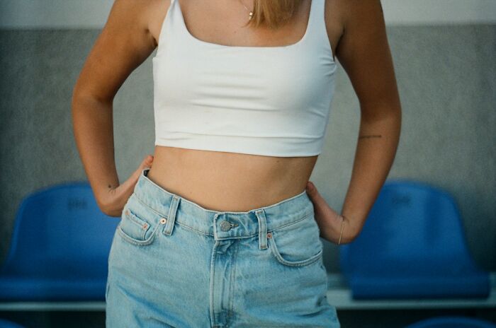 Woman in a white tank top and jeans, standing with hands on hips, representing niche facts about the female body.