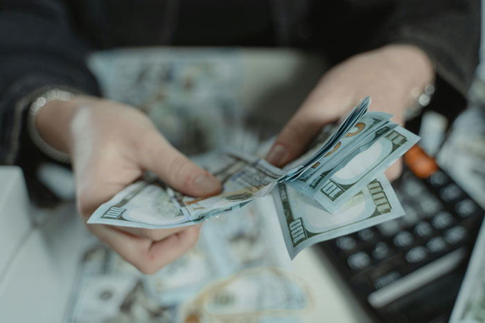 Person counting money with a calculator in the background, related to childfree woman and family vacation decisions.