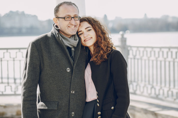 Father and daughter smiling outdoors, related to road trip and anxious feelings.