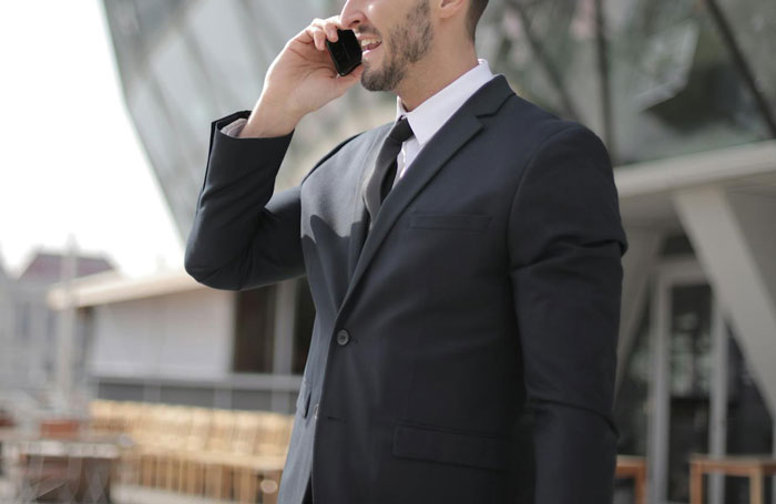 Man in a suit talks on a phone outdoors, related to anxious daughter incident.