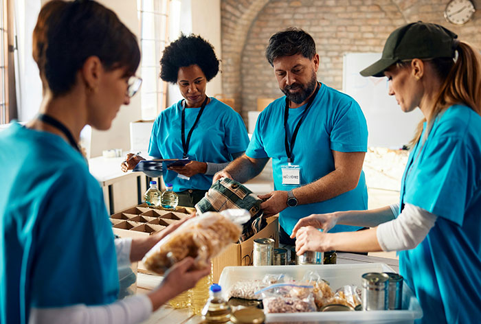 Volunteers in blue shirts organizing food donations at a food bank.