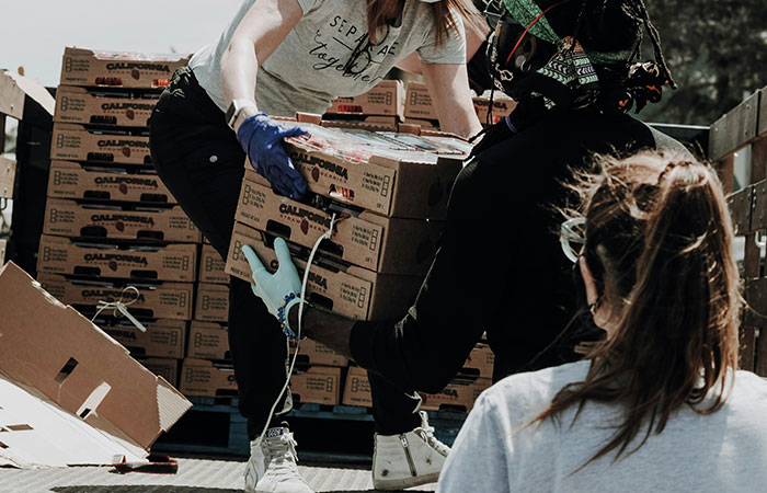 Volunteers at a food bank unloading boxes from a truck, engaging in teamwork and community service.