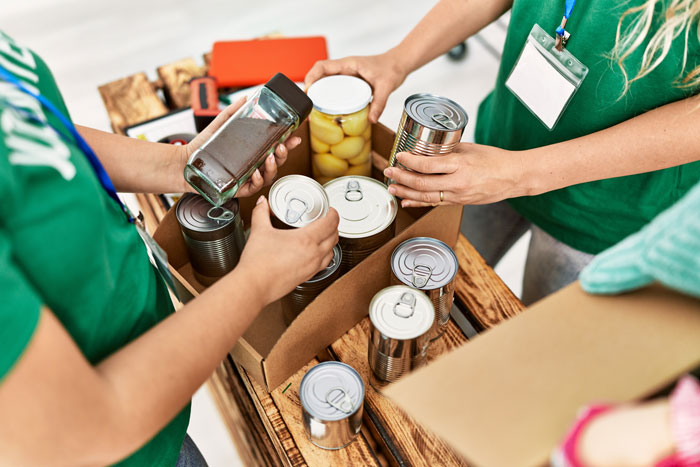 Two people packing canned food and glass jars at a food bank.