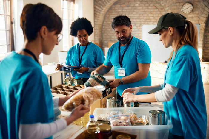 Volunteers in blue shirts sorting food donations at a food bank.