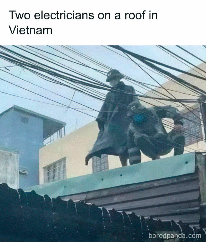 Two electricians on a roof in Vietnam, dressed like a "final boss," surrounded by power lines.