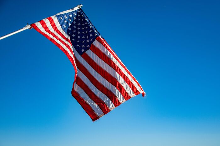 American flag waving against a clear blue sky, representing classic boomer ideals and values.