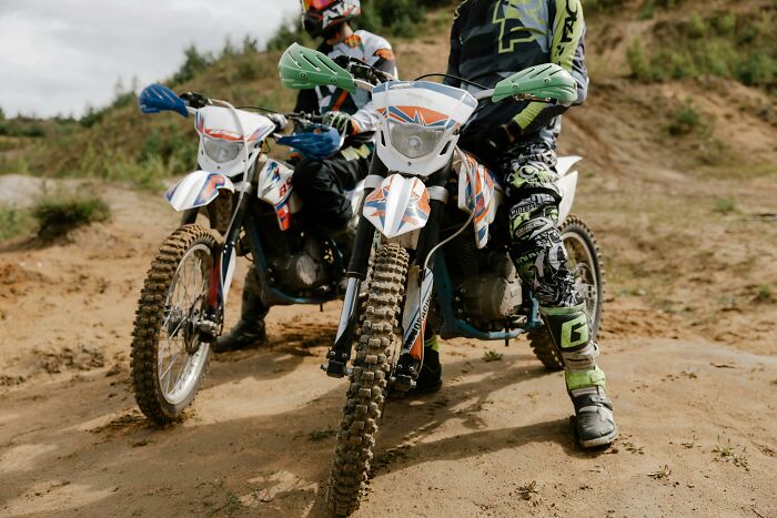 Two motorcyclists on dirt bikes in action, showcasing outdoor adventure and energy.