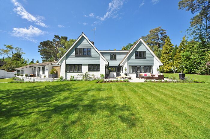 Modern house with lush green lawn under a clear blue sky reflecting generational lifestyle choices.