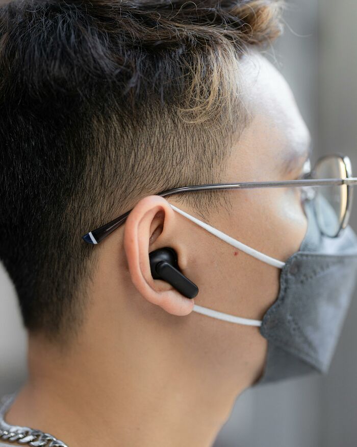 Gen Zer wearing glasses, a mask, and earbuds, reflecting modern style and technology preferences.