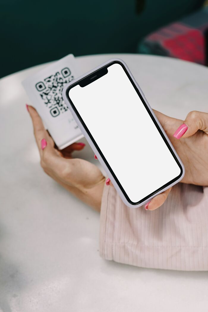 "Person with pink nails holding a smartphone displaying a blank screen, above a QR code card, symbolizing Gen Z takes."