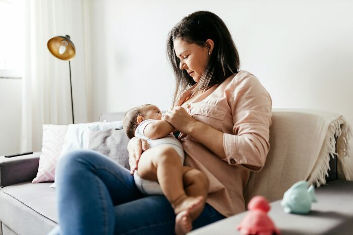 Woman breastfeeding a baby on a sofa, representing a niche fact about the female body.