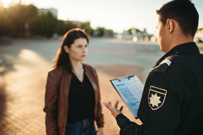 Police officer talking to a woman outdoors after a quarrel; focus on relationship conflict.