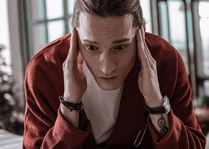 Man looking stressed, wearing a red sweater, highlighting family conflict and entitlement issues.