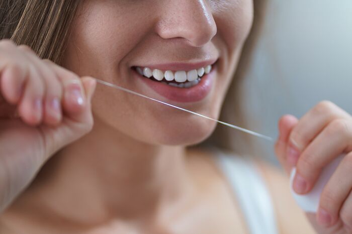 Woman flossing teeth, showcasing travel must-have for better packing efficiency.