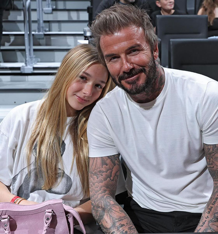 Father and daughter sitting together, smiling at a sports event.