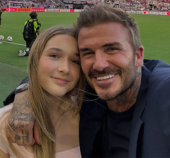 Father and daughter smiling at a soccer stadium, highlighting family bonding moments.