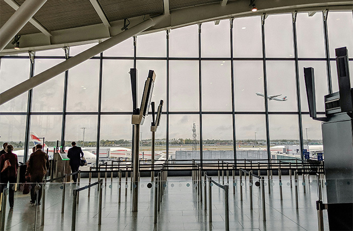 Airport terminal with passengers; a plane takes off, highlighting emergency landing and medical crisis issues.