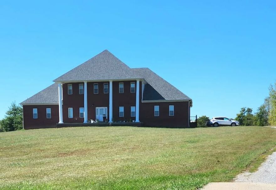 Unusual architecture of a brick house with oversized roof, showcasing design choices that might be considered for architecture shaming.