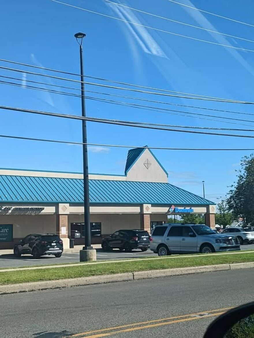 Awful architecture: a mismatched building with a blue roof and a franchise sign, surrounded by parked cars.