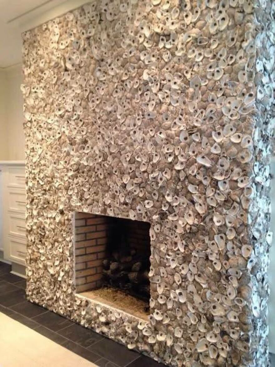 Unusual architectural design featuring a wall covered in oyster shells with a fireplace.