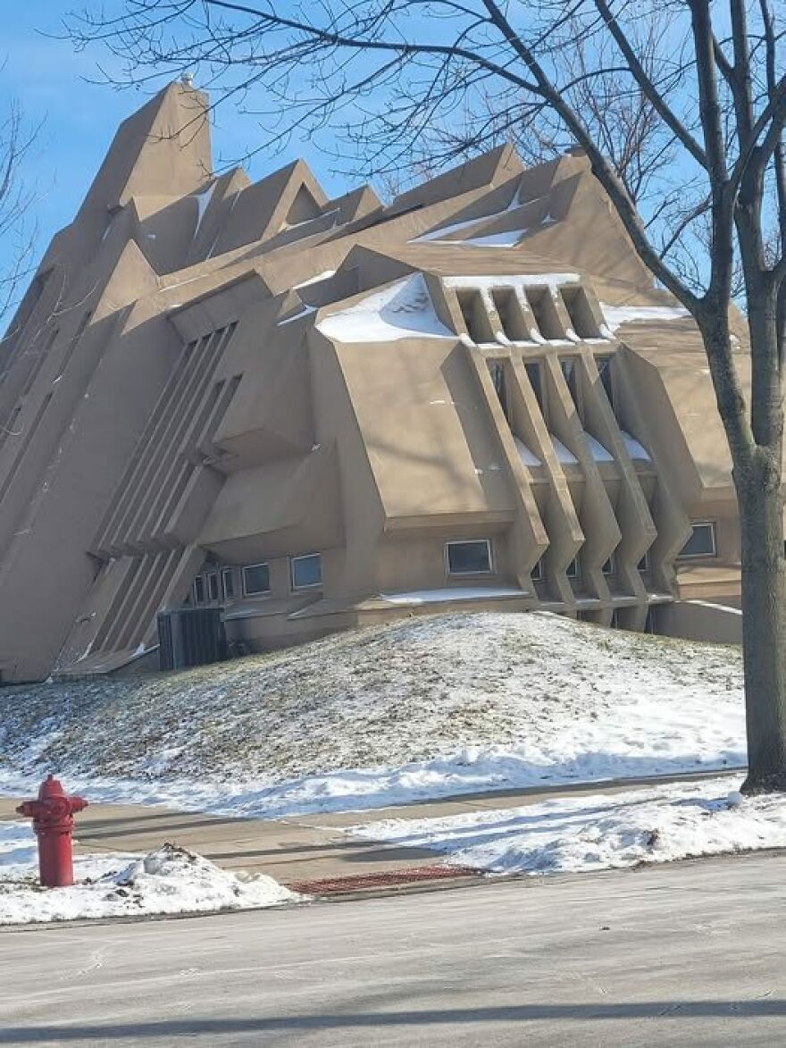 Unusual, angular architecture of a beige building with snow-covered ground and a red fire hydrant in the foreground.