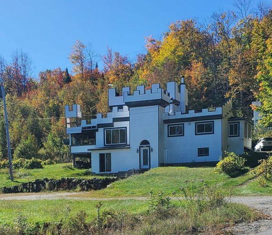 Unusual architecture resembling a small castle, set against a backdrop of autumn trees.