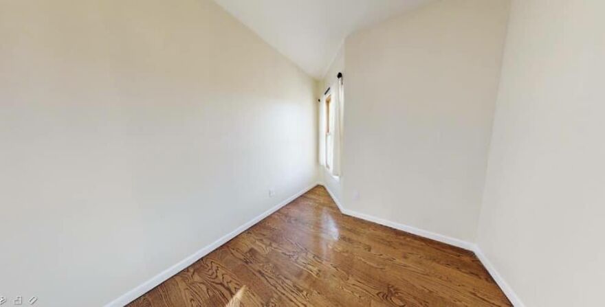 Narrow triangular room with wooden floor and a single window, illustrating architecture shaming.