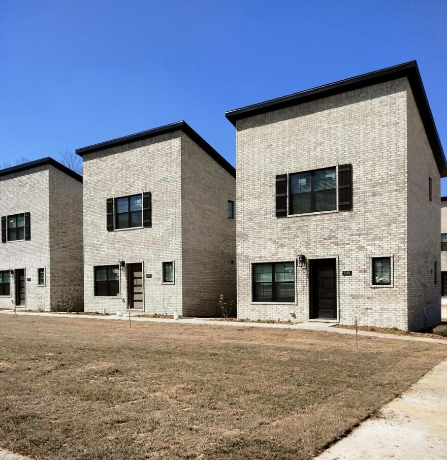 Minimalist brick buildings with flat roofs under a clear blue sky, exemplifying architecturally shamed structures.