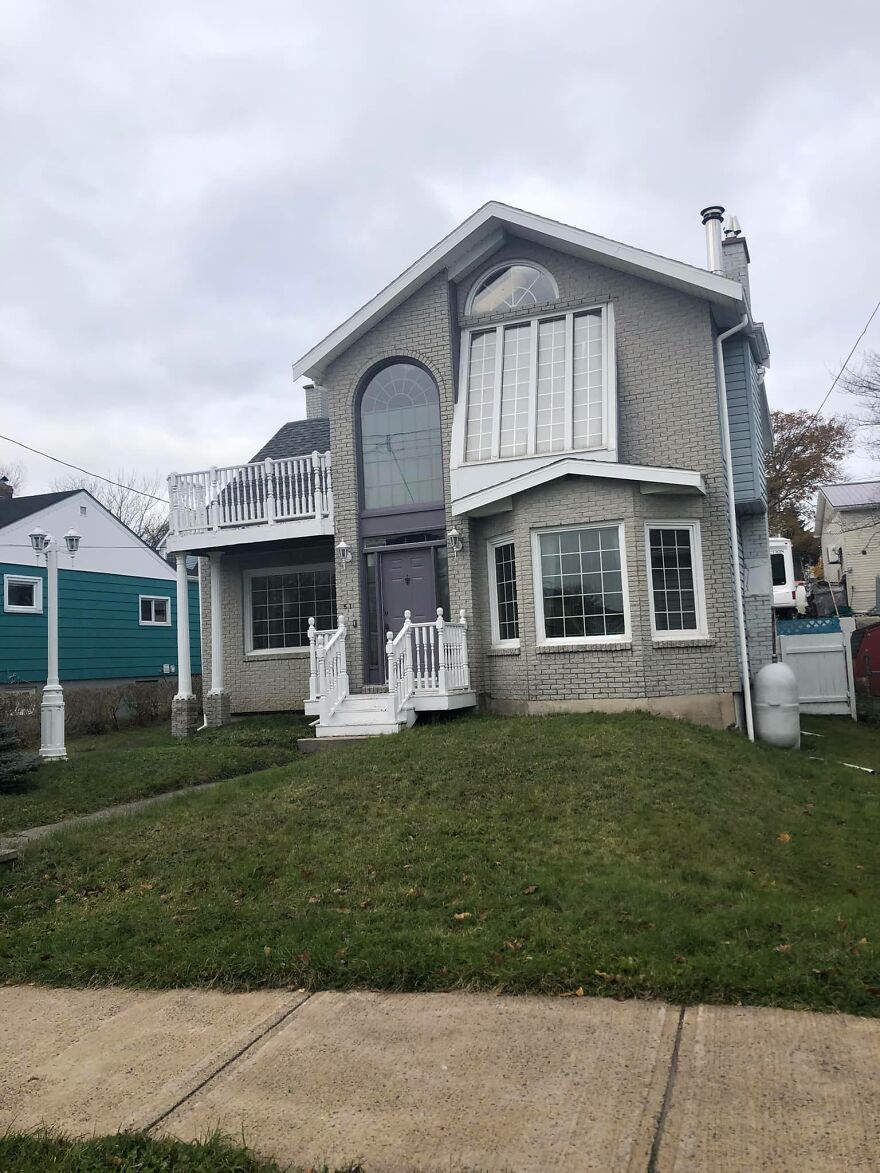 Unusual architectural design of a gray house with mismatched windows and awkward proportions.