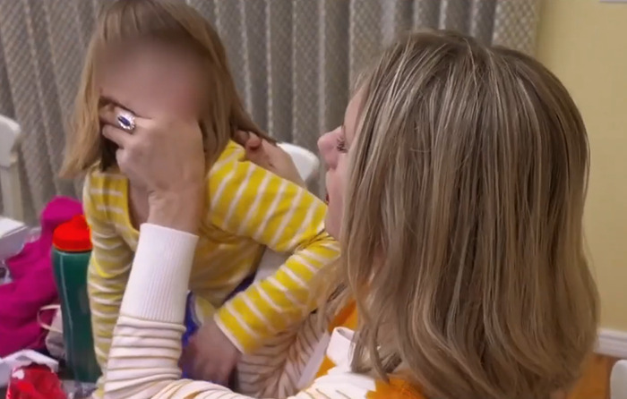 A woman holding a child in a yellow striped shirt, related to the momfluencer abuser docuseries.